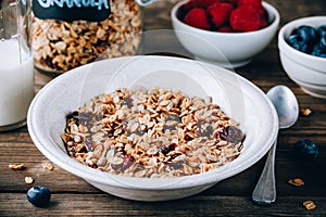 Homemade granola cereal with oats and nuts and dry cranberries. Healthy breakfast with milk and berries.