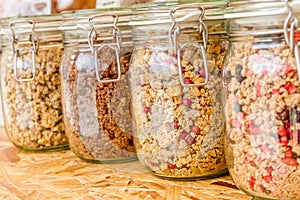 Homemade granola in jar on rustic kitchen table, healthy breakfast of oatmeal muesli, nuts, seeds and dried fruit