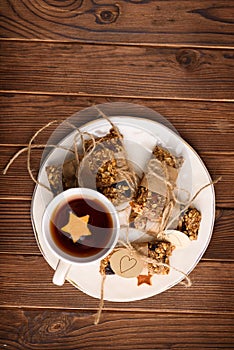 Homemade granola oatmeal energy bars, and cup of tea on white plate, healthy snack, copy space on wood desk