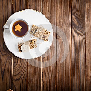 Homemade granola oatmeal energy bars, and cup of tea on white plate, healthy snack, copy space on wood desk