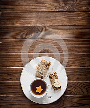 Homemade granola oatmeal energy bars, and cup of tea on white plate, healthy snack, copy space on wood desk