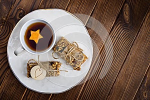 Homemade granola oatmeal energy bars, and cup of tea on white plate, healthy snack, copy space on wood desk