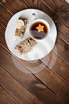 Homemade granola oatmeal energy bars, and cup of tea on white plate, healthy snack, copy space on wood desk