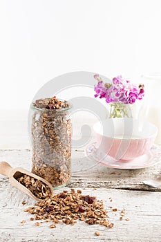 Homemade granola in open glass jar on white wooden background