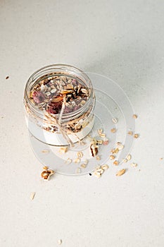 Homemade granola parfait. Quick healthy breakfast greek yogurt, granola with dried berries and nuts in glass jar on stone table