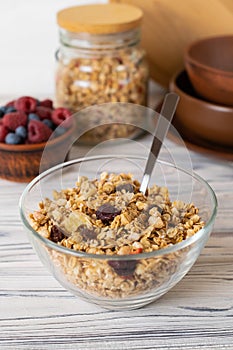 Homemade granola with raisins, nuts and berries in a glass bowl