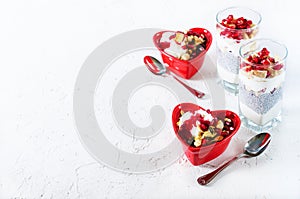 Homemade granola with yogurt in red heart plate on white table. Romantic breakfast. Free space for your text.