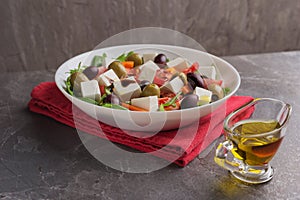 Homemade Greek salad on a white plate on dark table ready to eat. Creative isometric style. Mediterranean cuisine. Healthy food.