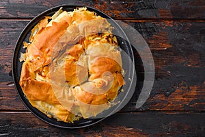 Homemade Greek spanakopita in backing pan  filo spinach eggs feta top view on dark wooden background