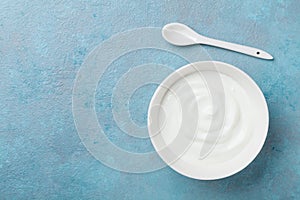 Homemade greek yogurt in bowl on blue stone table top view.