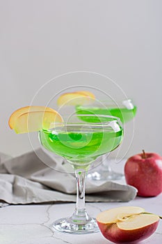 Homemade green apple martini cocktail with apple pieces in glasses vertical view