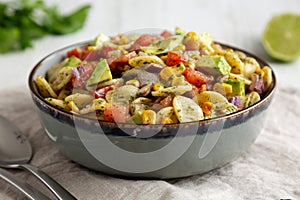 Homemade Grilled Corn Summer Pasta Salad in a Bowl on a white wooden background, low angle view. Close-up