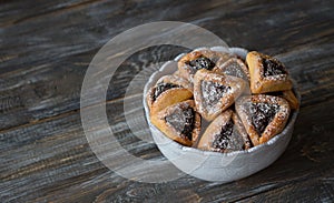 Homemade hamantashen cookies Haman`s ears with poppy seeds and apples on a wooden background. Traditional pastries for Purim,