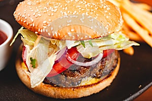 Homemade hamburger and french fries on black plate.