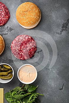 Homemade hamburger. Raw beef patties, sesame buns with other ingredients, on gray stone background, top view flat lay, with copy
