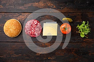 Homemade hamburger. Raw beef patties, sesame buns with other ingredients, on old dark  wooden table background, top view flat lay