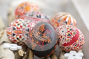 Homemade handmade painted Easter eggs on birch branches on grey wooden tray, traditional hnadcraft eggs, white flowers