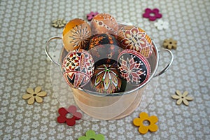 Homemade handmade painted Easter eggs in decorative old pink color tin on flowered tablecloth with decorative flowers
