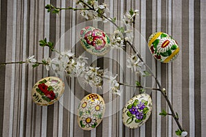 Homemade handmade painted Easter eggs on striped tablecloth decorated with blackthorn sloe branch