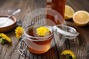 Homemade healthy dandelion syrup in a glass bottle, decorated with fresh flowers