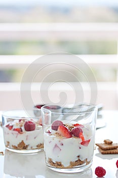 Homemade healthy dessert in glass with yogurt, fresh fruits and cookies for breakfast