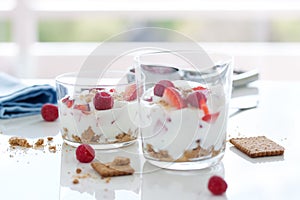 Homemade healthy dessert in glass with yogurt, fresh fruits and cookies for breakfast