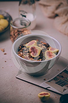 Homemade healthy granola with fresh figs and honey drizzle in a breakfast bowl on pink table