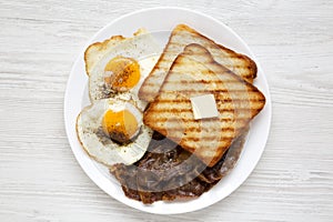 Homemade Healthy Sunnyside Eggs Breakfast on a white plate on a white wooden background, top view. Flat lay, overhead, from above