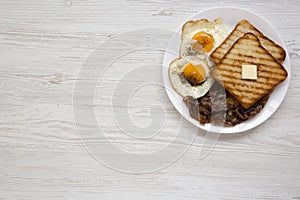 Homemade Healthy Sunnyside Eggs Breakfast on a white plate on a white wooden surface, top view. Flat lay, overhead, from above.