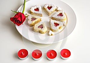 Homemade Heart shaped Almond Linzer cookies on white plate. Romantic set up red roses and candle lights ffor anniversary