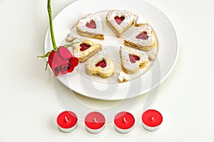 Homemade Heart shaped Almond Linzer cookies on white plate. Romantic set up red roses and candle lights ffor anniversary