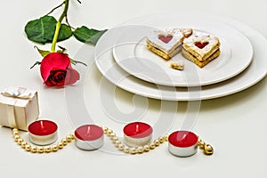 Homemade Heart shaped Almond Linzer cookies on white plate. Romantic set up red roses and candle lights ffor anniversary