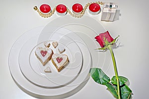 Homemade Heart shaped Almond Linzer cookies on white plate. Romantic set up red roses and candle lights ffor anniversary