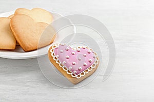 Homemade heart shaped cookies and plate on wooden table.