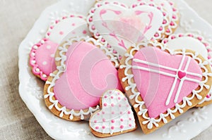 Homemade heart shaped sugar cookies with icing on white plate