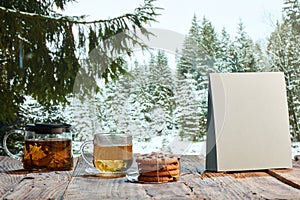 Homemade herbal or fruit tea. Glass pot, cup and sweets on wooden table over natural landscape background. Beauty, art