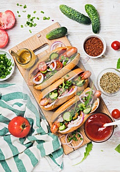 Homemade hot-dogs with fresh vegetables and spices over white background