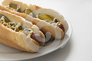 Homemade hot dogs with sausages and pickled cucubers in plate, isolated. White background