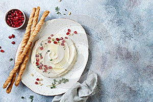 Homemade hummus with pomegranate, thyme, olive oil and pine nuts with grissini bread sticks. Middle Eastern traditional food