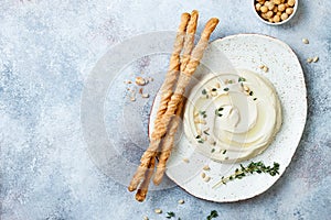 Homemade hummus with thyme, olive oil and pine nuts with grissini bread sticks. Middle Eastern traditional and authentic arab food