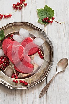 Homemade ice cream of red currant in shape of heart and on vintage dish and wooden background. Top view. Frozen drinks.