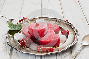 Homemade ice cream of red currant in shape of heart and on vintage dish and wooden background. Top view. Frozen drinks.