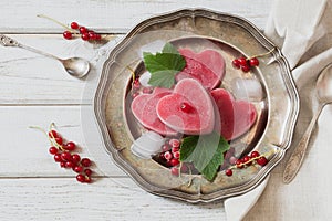 Homemade ice cream of red currant in shape of heart and on vintage dish and wooden background. Top view. Frozen drinks.