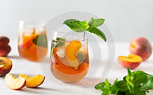 Homemade iced lemonade with ripe peaches and fresh mint. Fresh peach ice tea in glasses on a white background with ingredients.