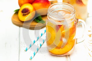 Homemade iced lemonade with ripe peaches. Fresh peach ice tea in a mason jar.