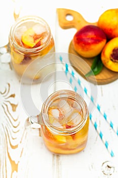 Homemade iced lemonade with ripe peaches. Fresh peach ice tea in a mason jar. Top view.