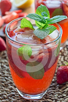 Homemade iced tea with strawberries and mint, vertical closeup