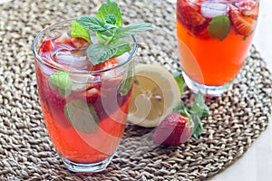 Homemade iced tea with strawberries and mint on wooden table, ho