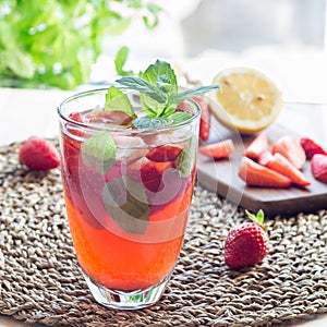 Homemade iced tea with strawberries and mint on a wooden table,