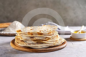 Homemade Indian flat bread Chapati or Roti on grey concrete background with butter ghee and flour